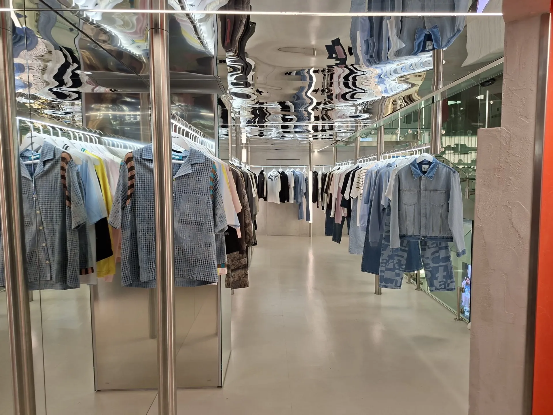 Una corsia del negozio con camicie e capi in denim appesi