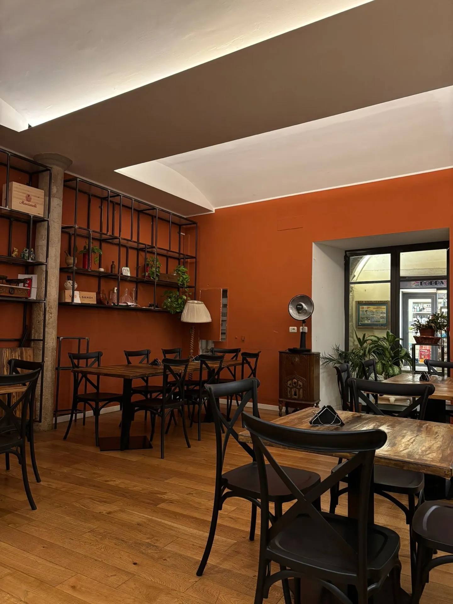 Sala di Dicaduca con parete arancione, scaffali e sedie in legno