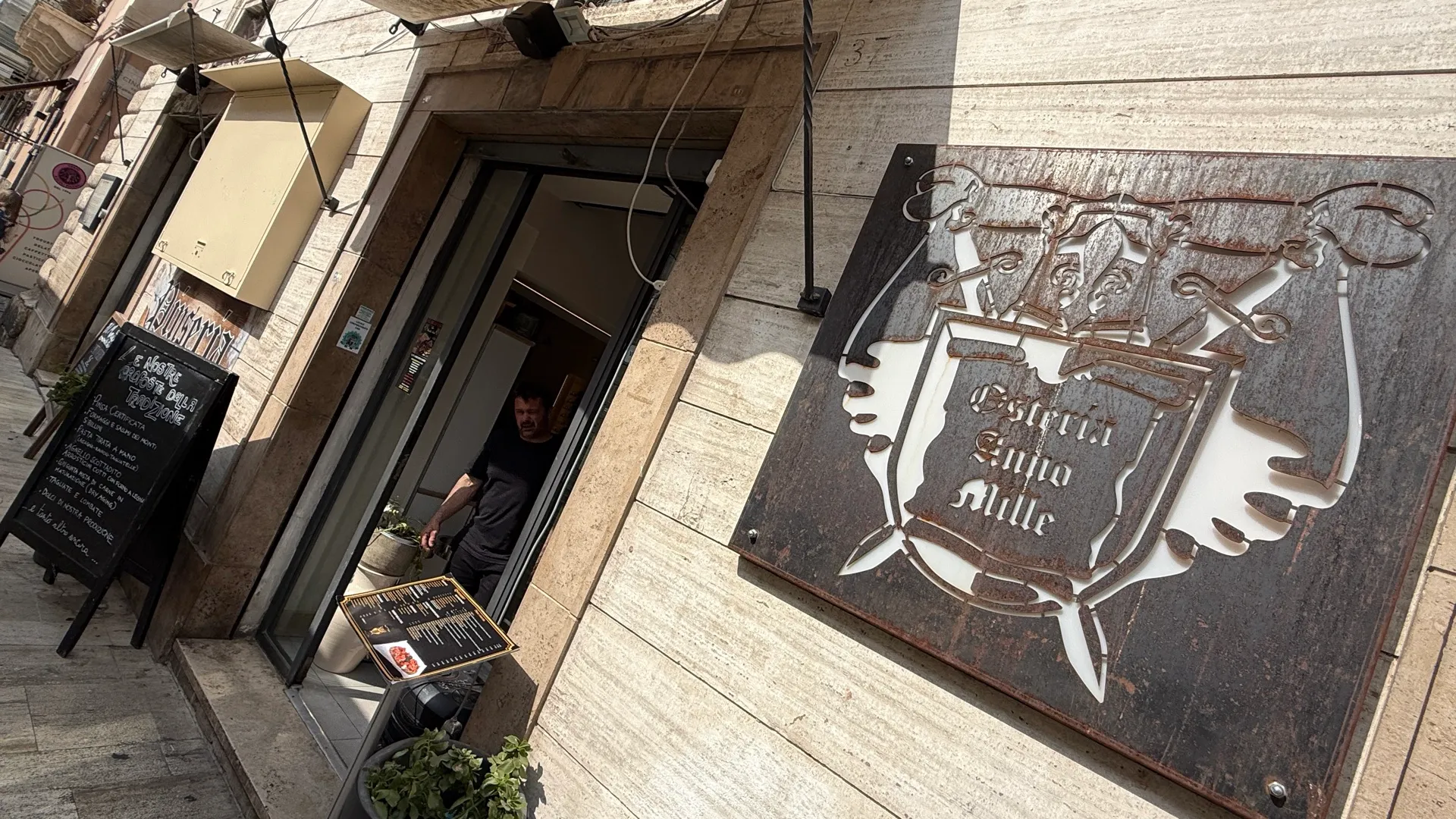 L'insegna in metallo e l'ingresso dell'Osteria Anno Mille in Piazza Arringo