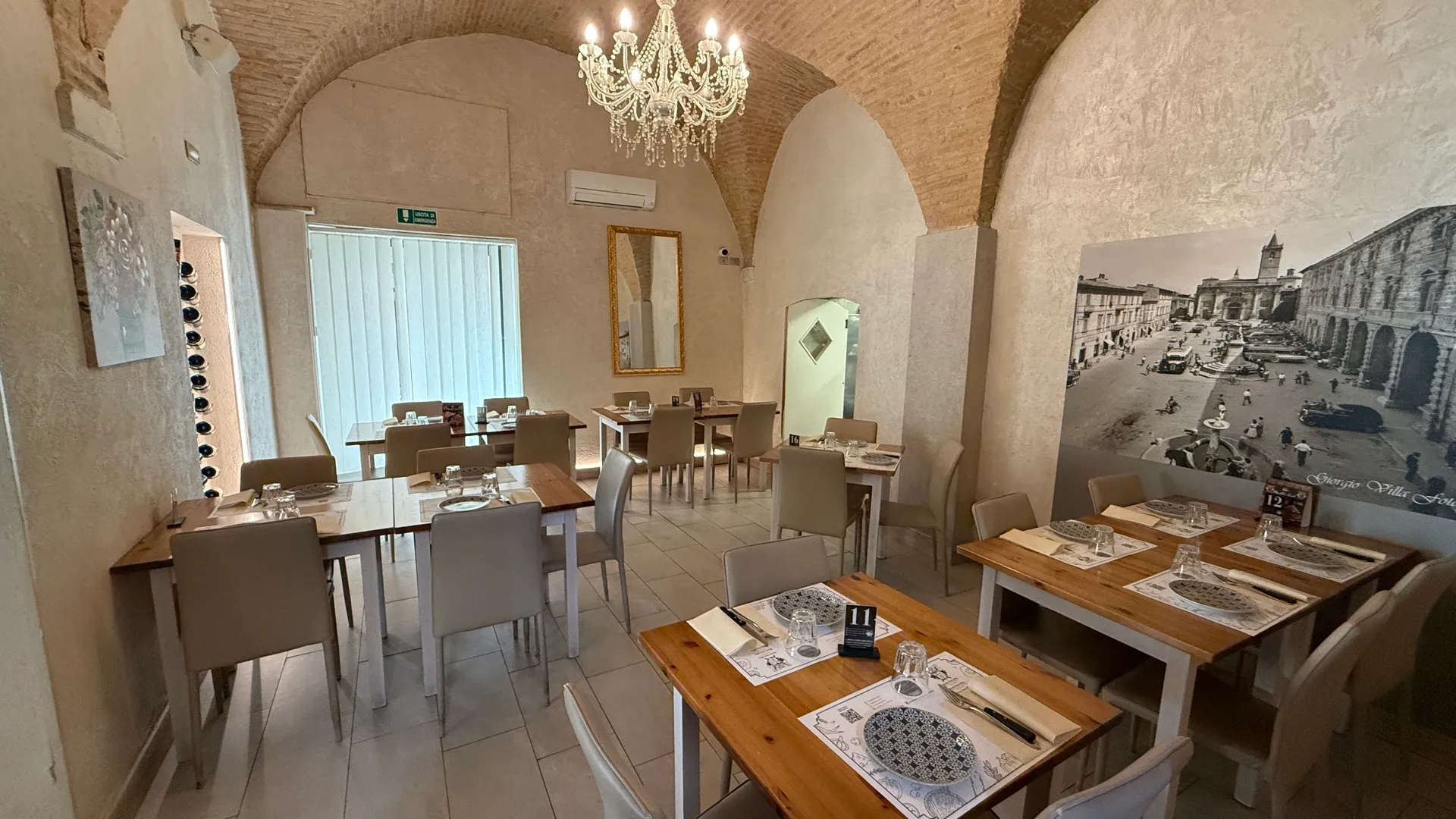 La sala a volte dell'Osteria Anno Mille con lampadario e tavoli apparecchiati