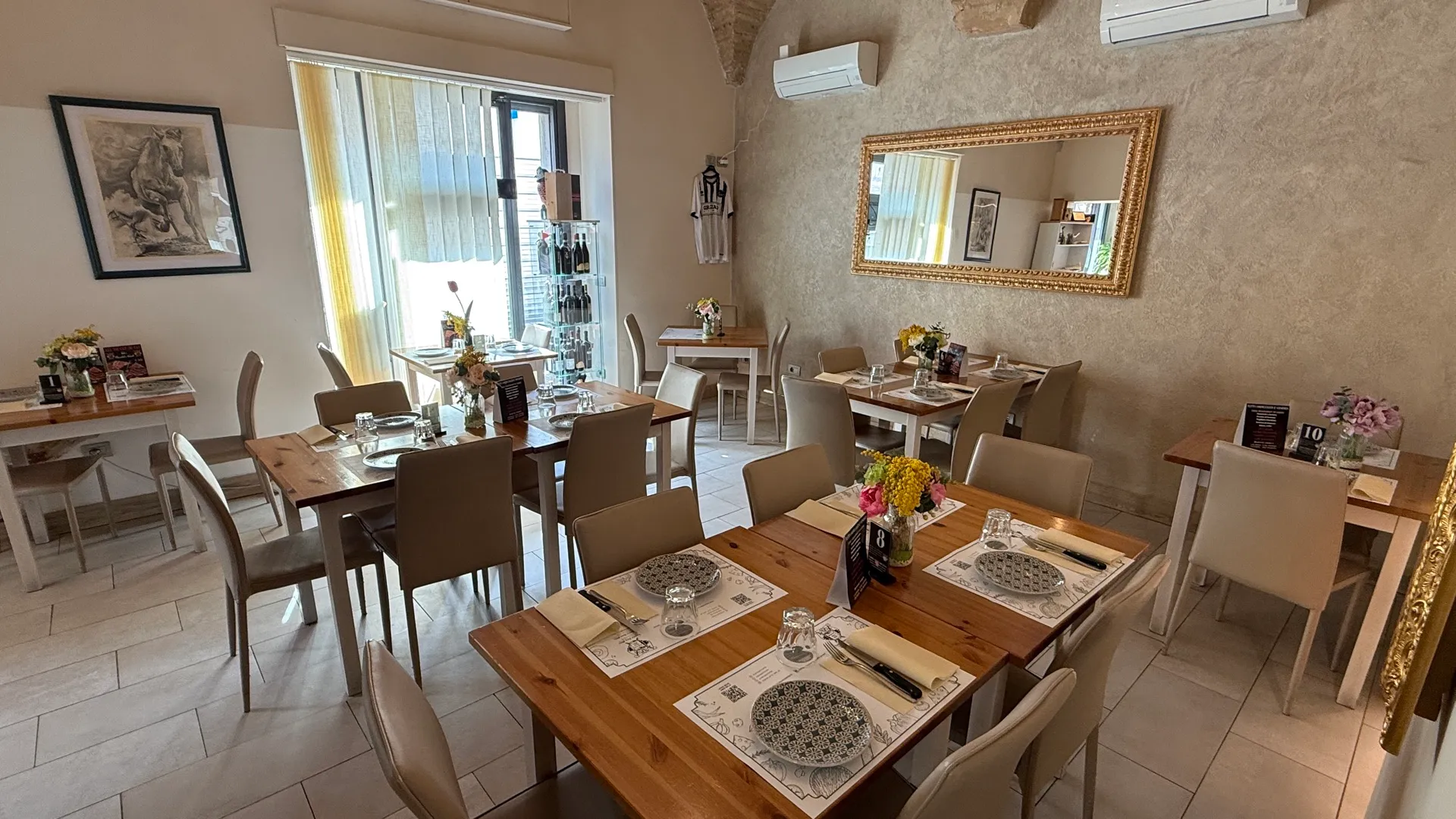 Angolo della sala con specchio dorato e tavoli in legno