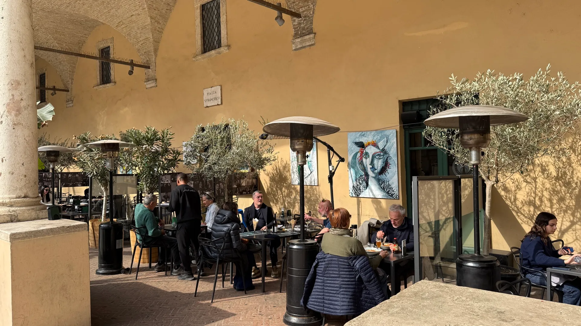 Clienti all'aperitivo ai tavoli sotto il chiostro
