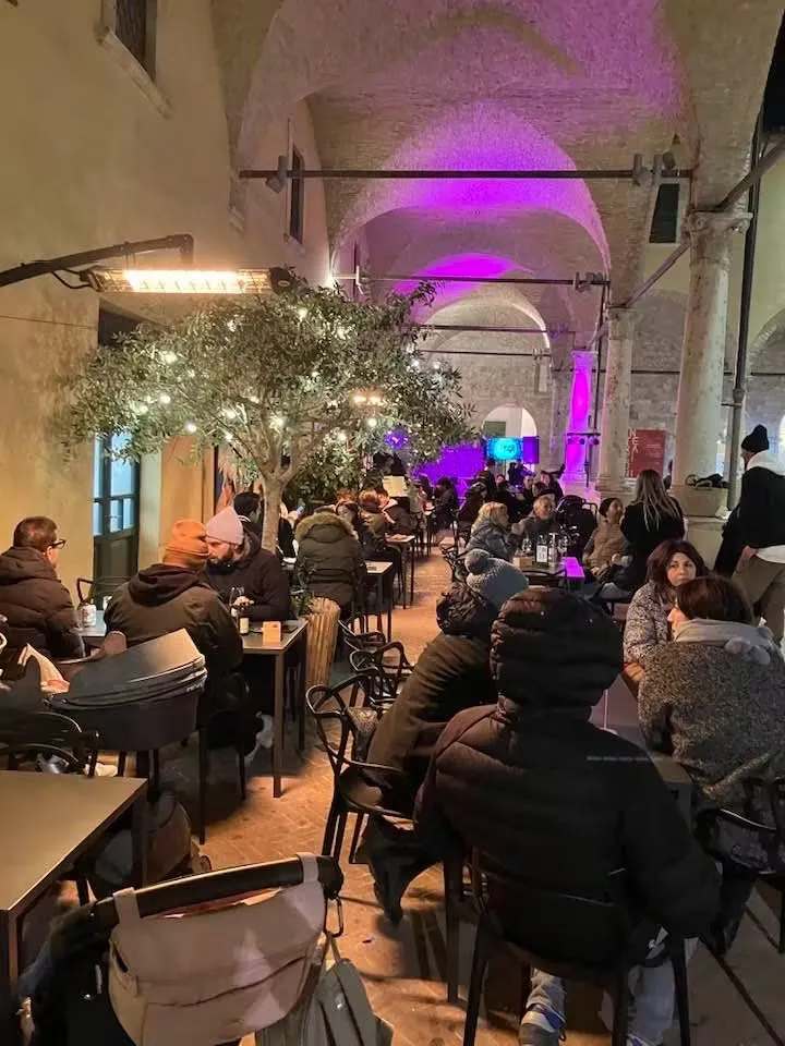 Serata invernale nel chiostro con stufe e luci colorate sulle volte