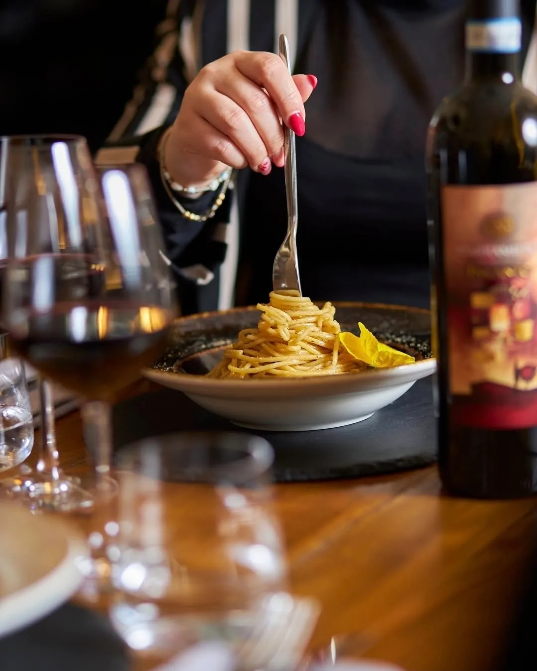 Piatto di spaghetti accompagnato da un calice di vino rosso