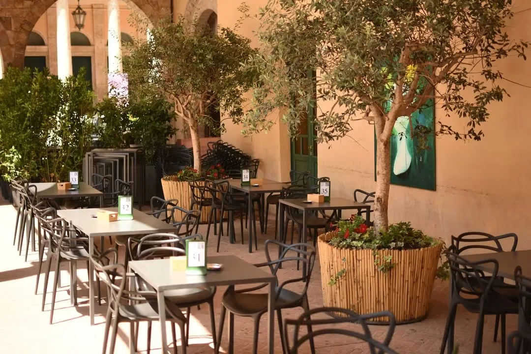 Tavoli e ulivi in vaso sotto il portico del chiostro